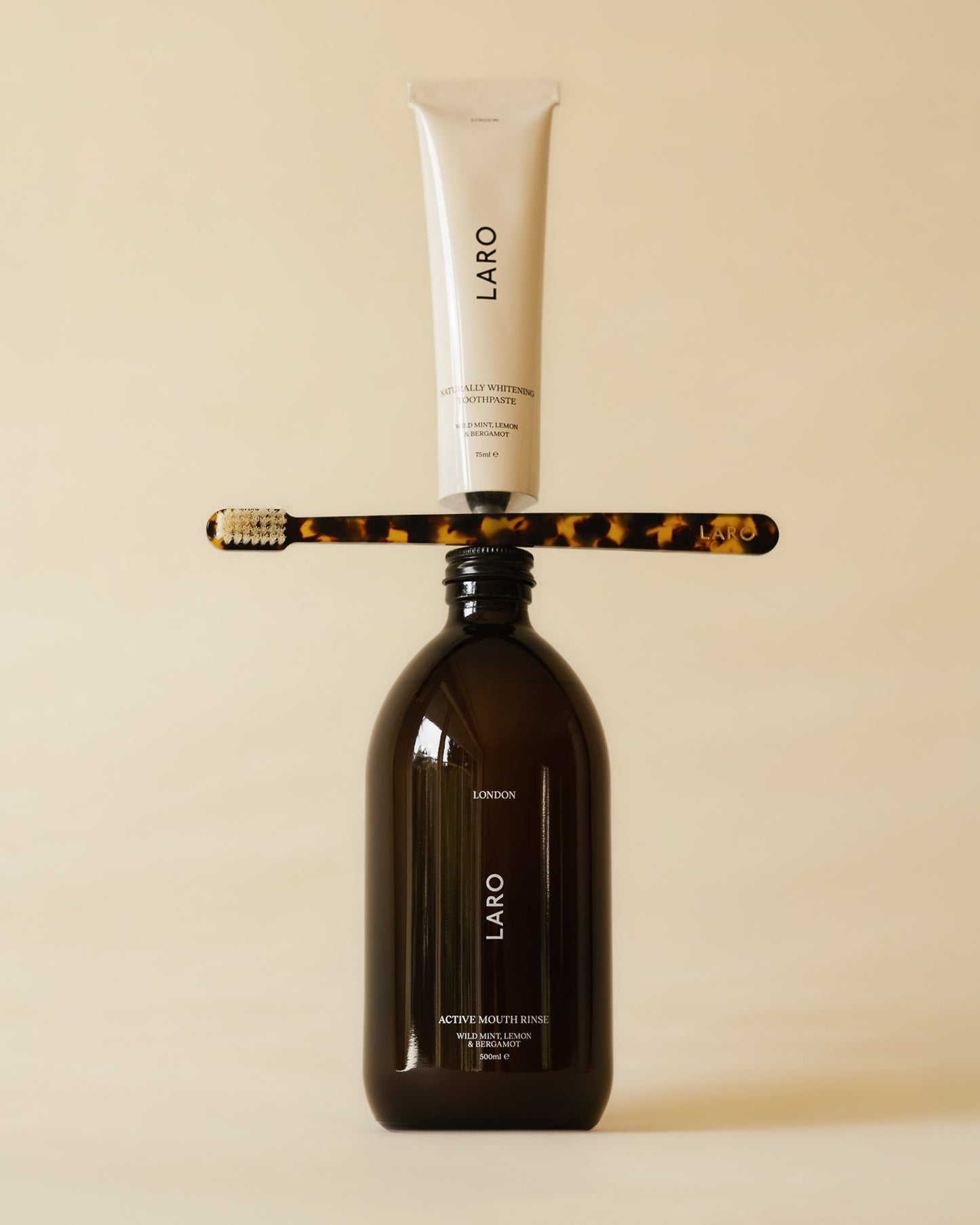 Laro oral care signature products with a toothpaste tube, toothbrush and mouthwash bottle on a beige background