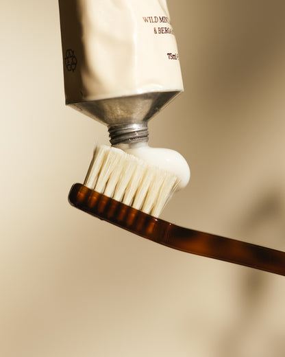 Toothbrush with toothpaste being applied on a beige background
