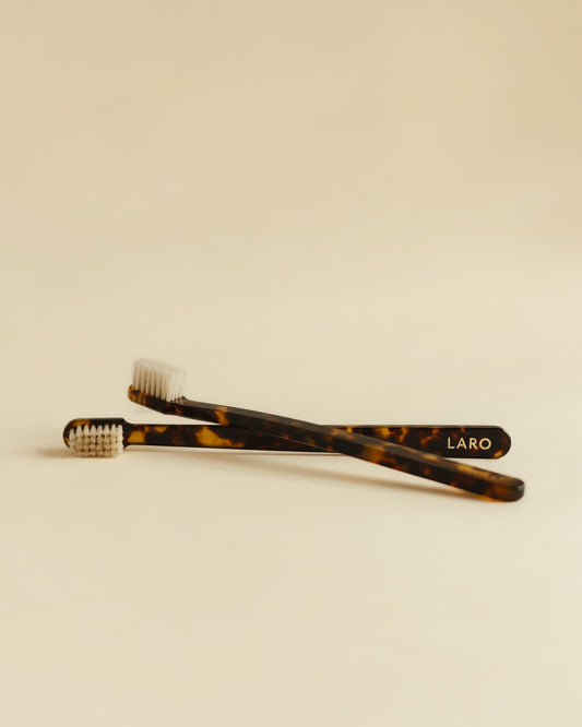 Two tortoiseshell toothbrushes with 'LARO' branding on a beige background