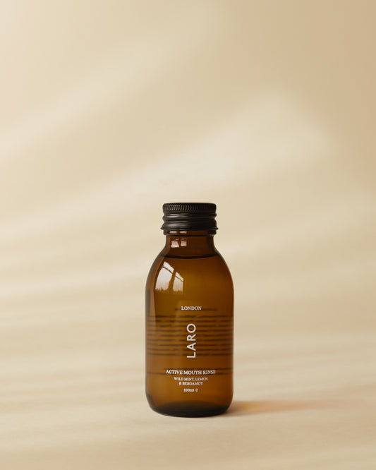 Brown travel mouth rinse bottle with black cap on a beige background